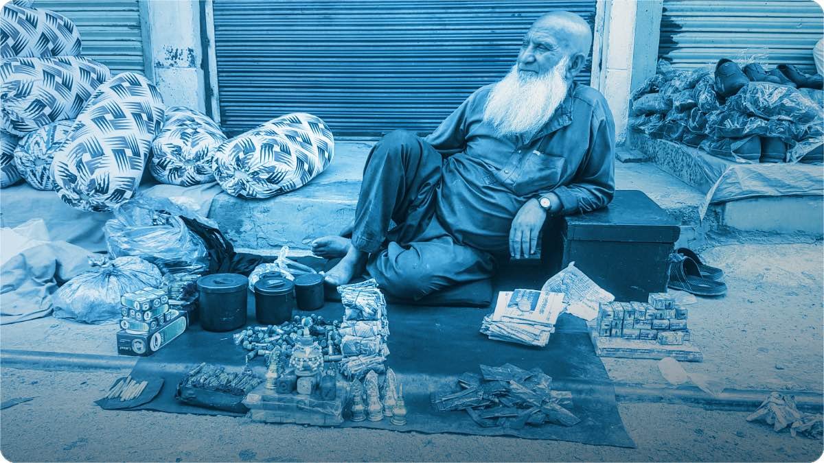 A street trader sitting beside the goods he has laid out for sale.