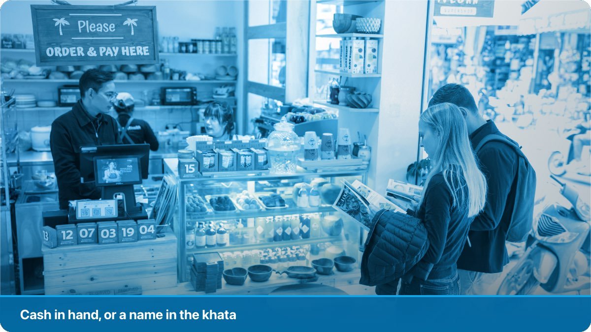 A shopkeeper taking notes from a customer at a busy neighbourhood counter.