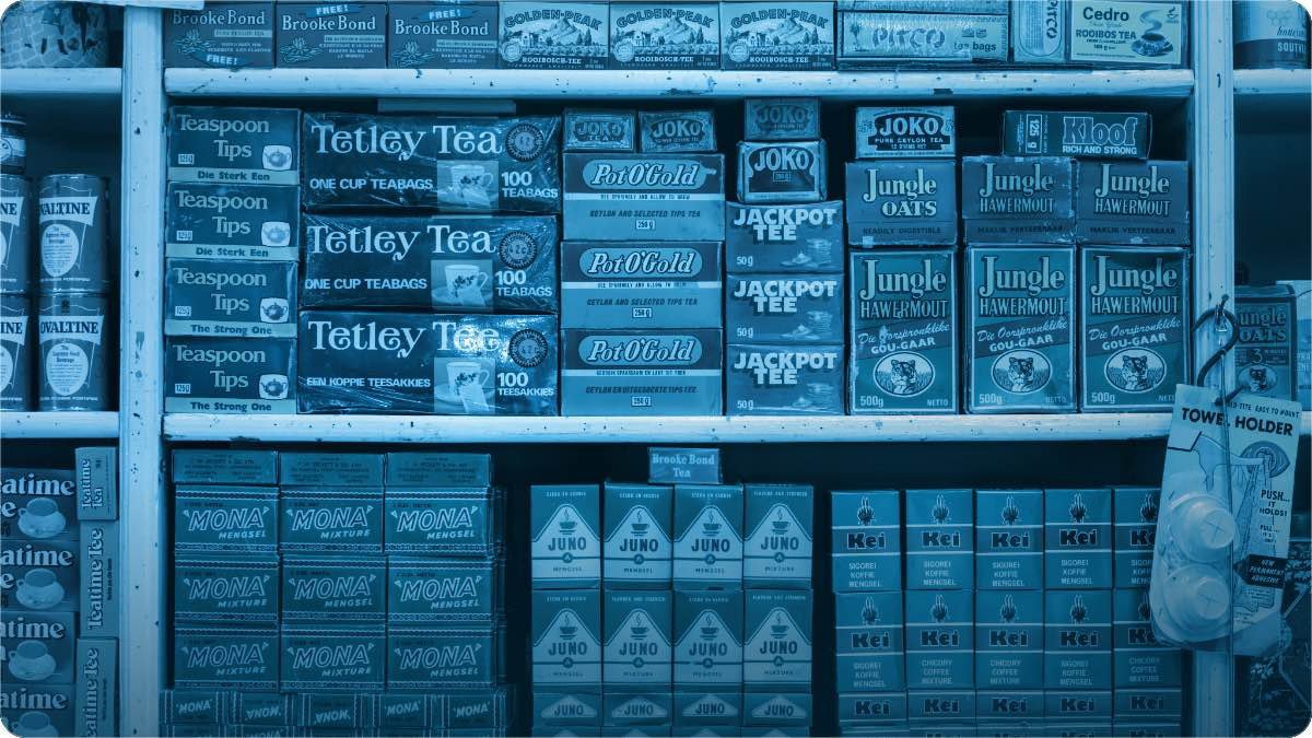 Shelves of packaged tea and snacks in a South Asian grocery shop, several versions of the same item side by side.