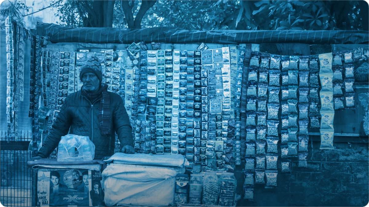 A street stall hung with rows of small packets, the vendor standing behind his wooden counter.