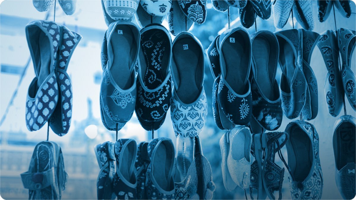 Rows of embroidered traditional shoes hanging on display at a shop, each pair tagged with its size.