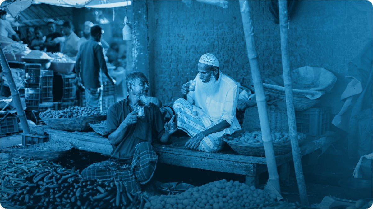 Do sabzi farosh masroof bazaar ke thele par baithe chai ke sath baat karte hue.