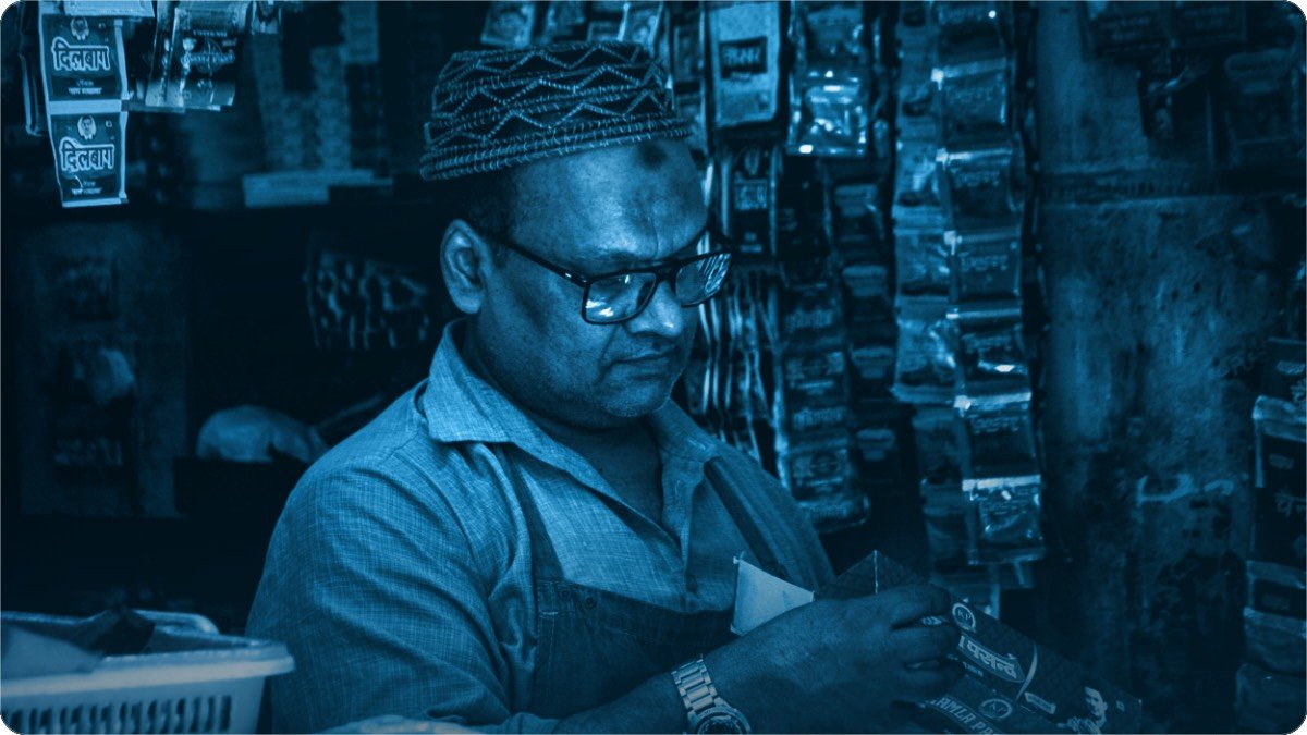 A shopkeeper counting cash notes at his counter at the close of the day.