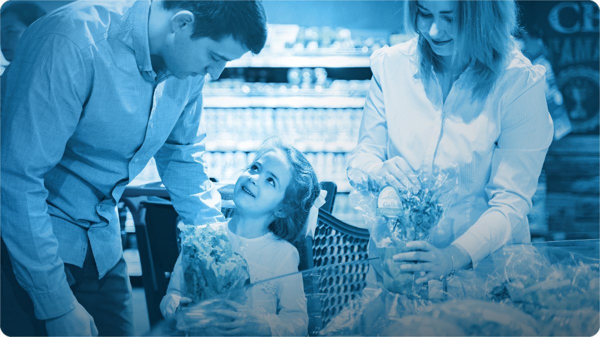 A family choosing groceries together in the aisle of a neighbourhood store.