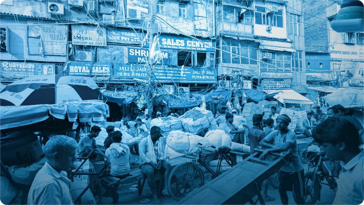 A crowded market street at its busiest, with loaded handcarts and shops packed on both sides.