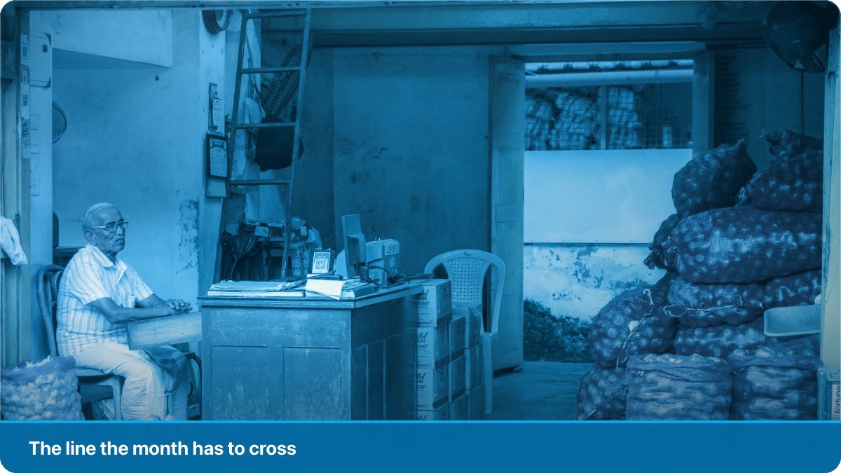 A shopkeeper sitting at his counter with the day's papers in front of him.