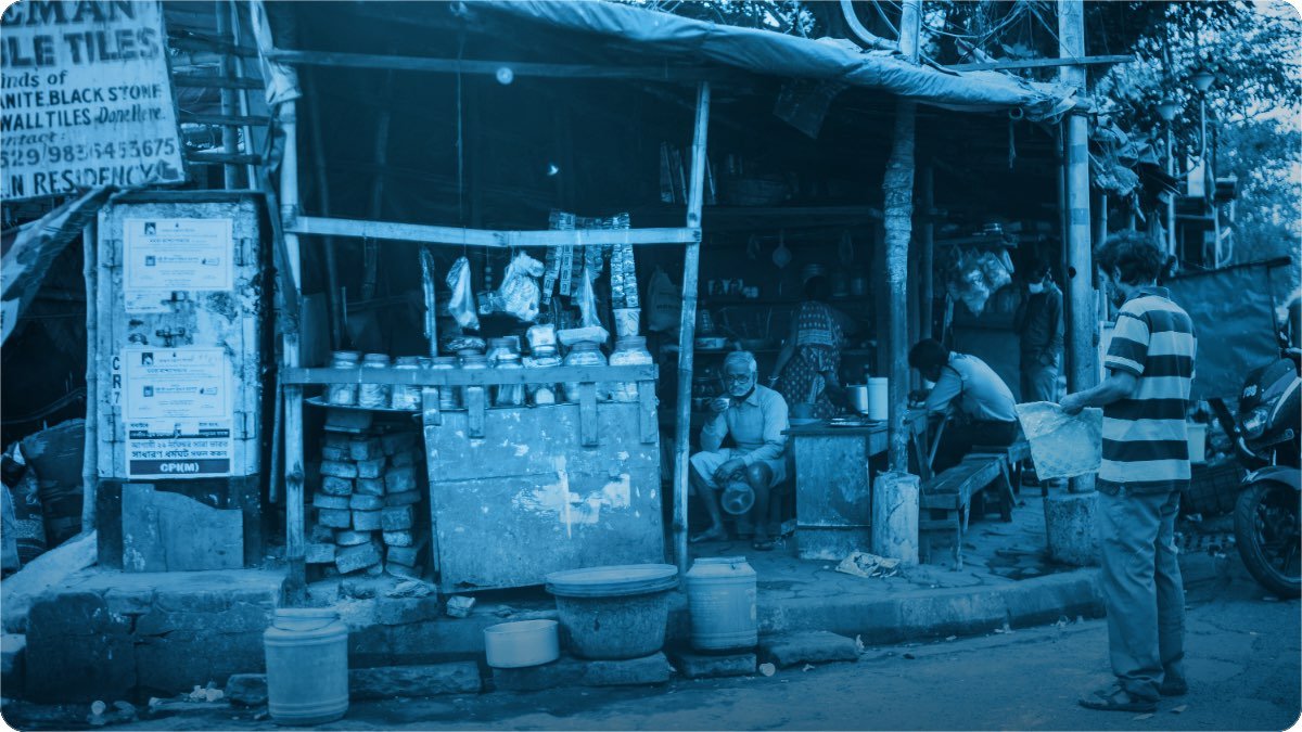 A roadside shop on a busy street, its front stacked with goods and customers standing outside.