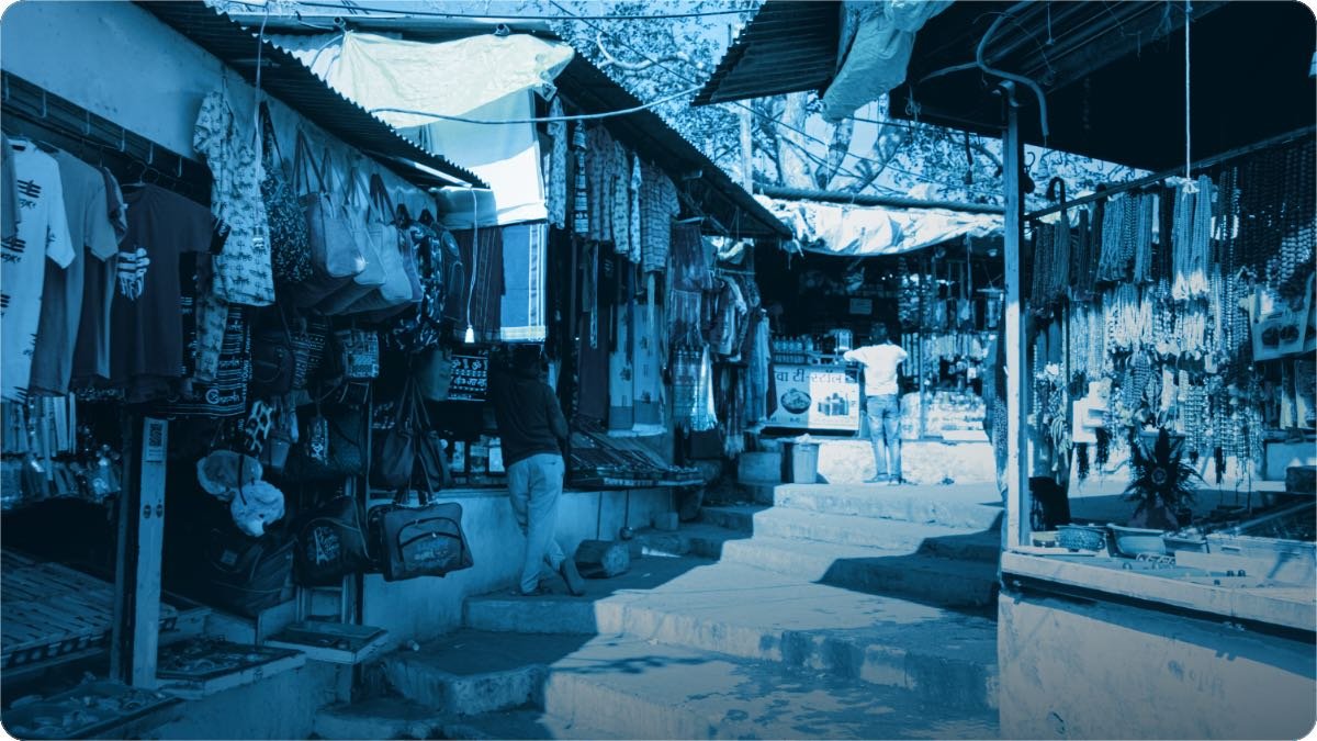 A market lane in India with stalls carrying bags, clothes and beads hung from every frame.