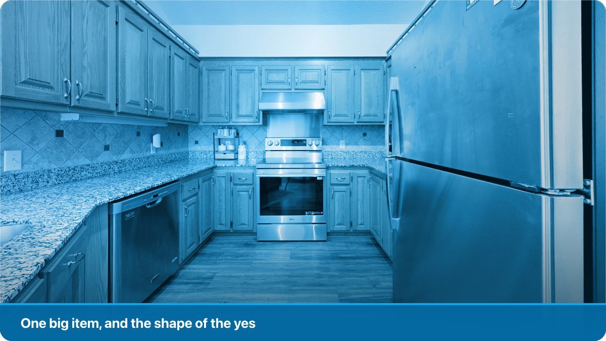 A new refrigerator in an electronics shop with a customer looking at it.