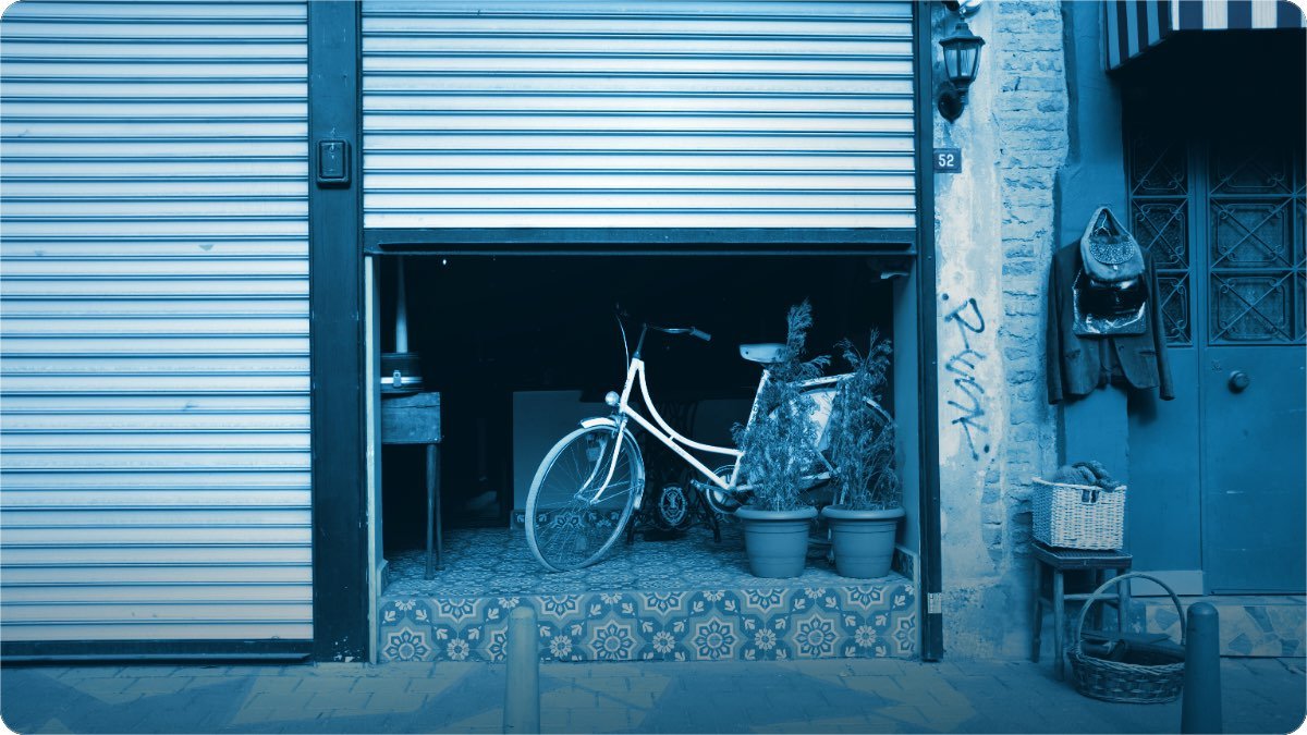 A closed shop shutter on a quiet street in the early evening.
