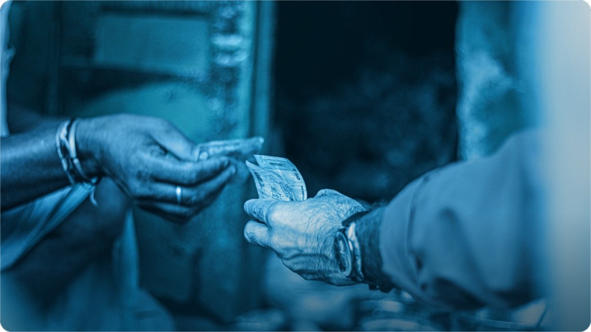 One person handing a banknote to another across a counter, only their hands visible.