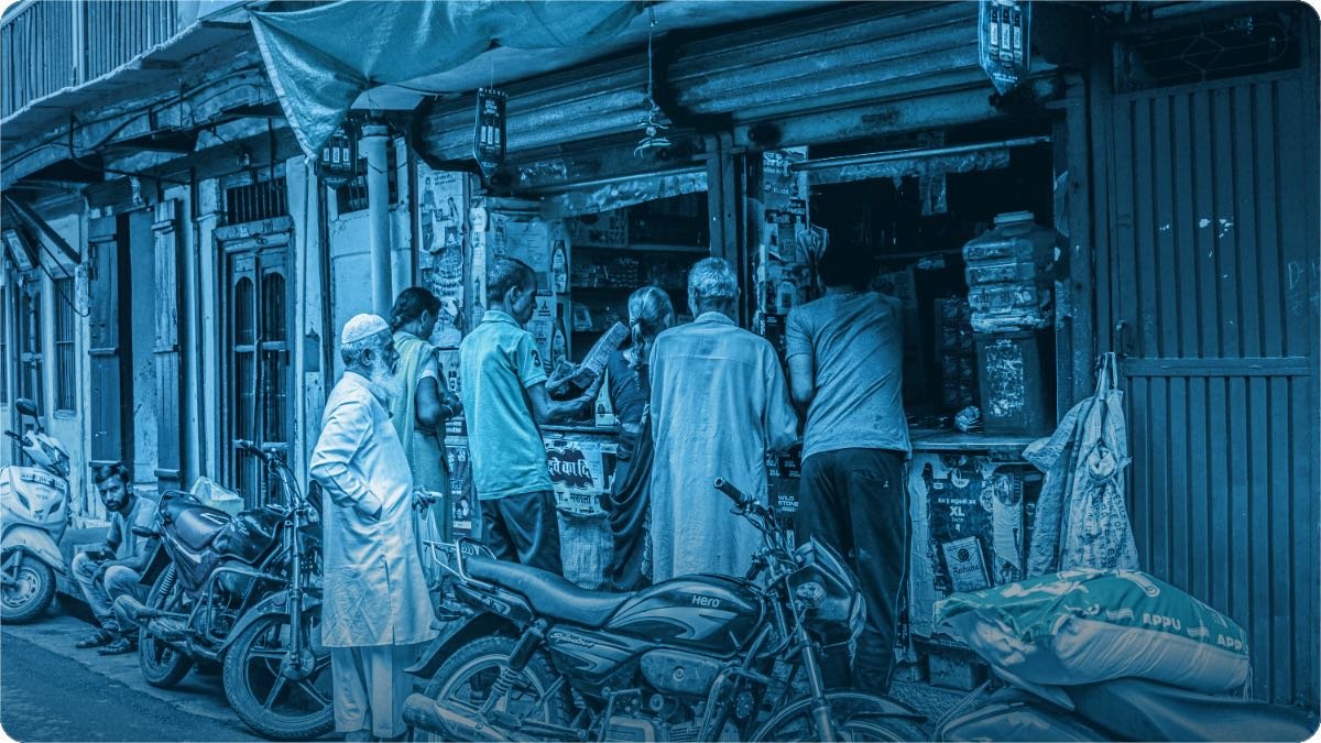 Chhoti si dukan ke counter par kai customer khare hain, bahar motorcycleon ki qatar lagi hai.